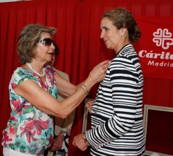 Su Alteza Real la Infanta Doña Elena recibe la insignia de la organización, durante su participación en una mesa petitoria por el día de la Caridad